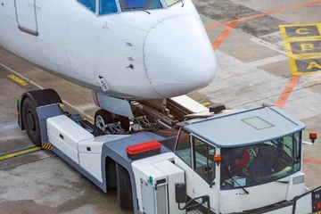 Rollo Airplane execute push back operation at airport, close up view. Tug tractor truck new type elevator chassis. © aapsky