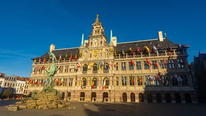 Poster View of Brabo Fountain in front of Antwerp City Hall richly ornamented with heraldic symbols, sculptures and flags Belgium, Flanders and countries of European Union and United Nations on Grote Markt.. © JackF