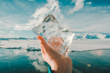 Close up man showing ice at glacier concept photo. Frozen beauty. First view hand photography with icebergs in sea on background. High quality picture for wallpaper, travel blog, magazine, article