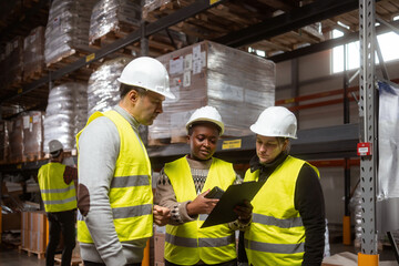 A multiracial group of people is working in a distribution warehouse, the manager is giving instructions to the workers.