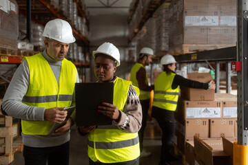 A multiracial group of people is working in a distribution warehouse, the manager is giving...