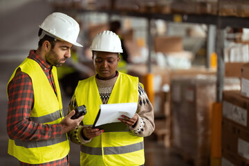 A shot of a man and woman working in a distribution warehouse, the manager is giving instructions to one worker.