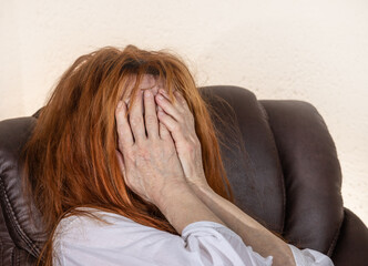 A woman with red hair is in despair and holds her hands in front of her face