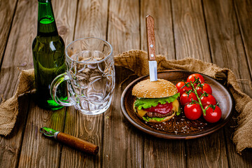 From above view of rustic serving classic beef burger with glass of beer on wooden table. gastro pub