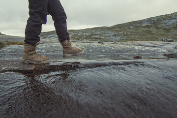 Tourist walking across small mountain river scenic photography. Picture of person with gloomy sky...