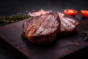 Delicious fresh juicy beef steak with spices and herbs on a dark concrete background