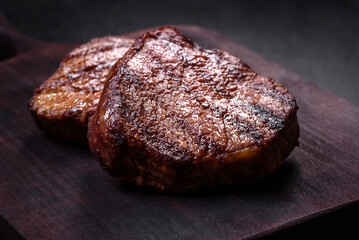 Delicious fresh juicy beef steak with spices and herbs on a dark concrete background