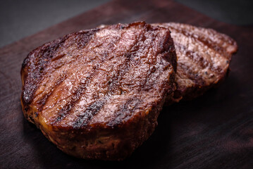 Delicious fresh juicy beef steak with spices and herbs on a dark concrete background