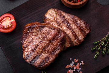 Delicious fresh juicy beef steak with spices and herbs on a dark concrete background