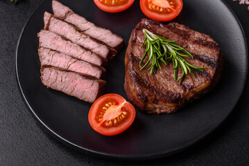 Delicious fresh juicy beef steak with spices and herbs on a dark concrete background
