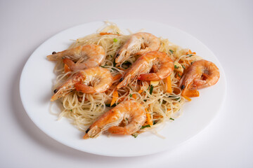 Spicy funchosa salad with shrimp on a white plate on a white background. A dish of Asian cuisine