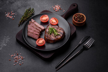 Delicious fresh juicy beef steak with spices and herbs on a dark concrete background