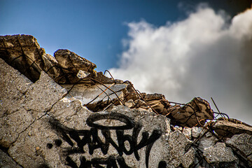 Destroyed concrete slabs with graffiti against a blue sky with white clouds