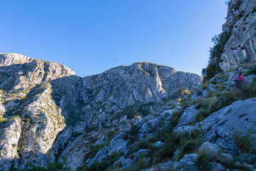 Idyllic hiking trail from Kotor to Derinski Vrh, Lovcen mountains, Dinaric Alps, Montenegro, Balkan Peninsula, Europe. Path is surrounded by steep cliffs and rock formations. Sunny summer day