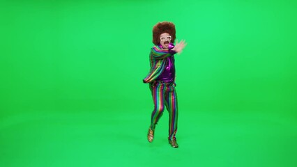 Retro dude in a multicolored suit dancing a funny dance on a green background, a festive mood, retro disco man is having fun at a new year's party. - Powered by Adobe