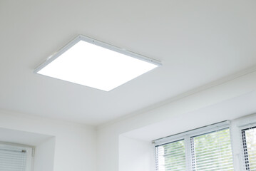 Suspended ceiling with modern LED lighting. Turned on lamps on the ceiling in office of white...