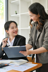 Happy young Asian female office worker is being trained by her boss, getting project compliments