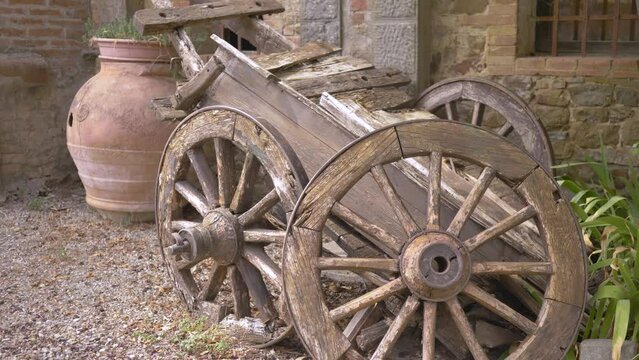 An old broken cart with wooden wheels near the walls of an abandoned building