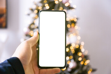 phone mockup on christmas tree background. Ordering gifts online, preparing for the New Year holidays