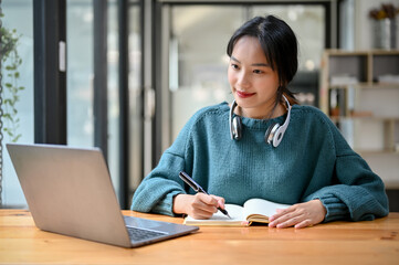 Pretty Asian female college student focusing on her homework or school project