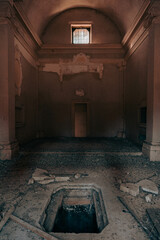 Mysterious hole in the floor of an abandoned church. Dirty little sacred place full of guano and debris. Opening of a dark ancient crypt.