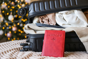 Passport with packed suitcase on the background of the Christmas tree. Tourism, travel for Christmas and New Year. Winter holidays. Airplane flight. Vacation in winter.