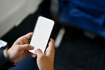 A male passenger using his smartphone during the flight. smartphone white screen mockup