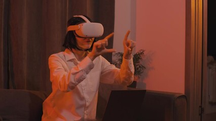 Beautiful young business woman wearing virtual reality headset and doing business using laptop and mixed reality. Girl studying in virtual reality - Powered by Adobe