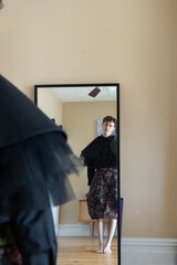 non-binary caucasian person with short hair getting dressed in mirror