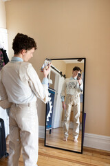 non-binary caucasian person taking selfie in mirror with smartphone