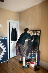 non-binary caucasian person with short hair getting dressed in mirror