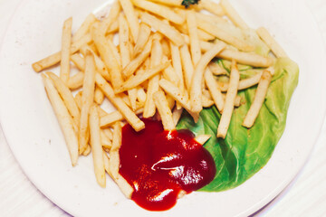 fried potatoes with ketchup and lettuce on a white plate