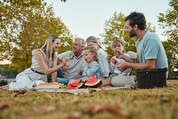Watermelon, love or big family in nature on a picnic eating healthy fruit or food on summer holiday vacation in Berlin. Grandparents, mother and happy father enjoy bonding or relaxing with children