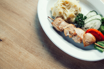 pork kebab ,mashed potatoes and slices of fresh vegetables in a plate