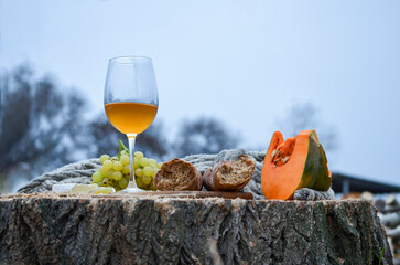 A glass of white wine stands on a wooden stump