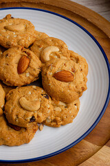 Homemade almond cookies in ceramic white plate on wood table background
