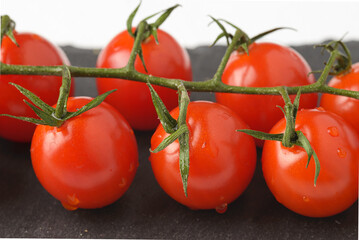 Cherry tomatoes with green leaves on dark plate