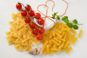 Raw uncooked pasta with cherry tomatoes on white background