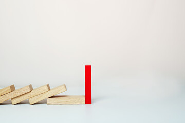 One red domino stands, and other wooden dominoes fall in a row. 