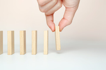 The hand puts dominoes to make a chain reaction