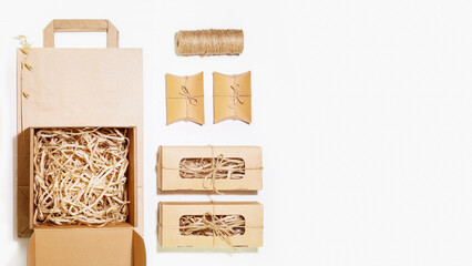 Eco friendly packaging concept. Cardboard boxes with shredded paper inside, paper bag and small gift boxes for packaging goods from online stores and delivery on white background with copy space