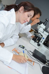 middle-age female scientist or tech writes report in modern laboratory