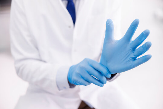 Doctor putting on protective latex gloves