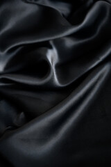 Silk background. Elegant black satin silk with waves, abstract background