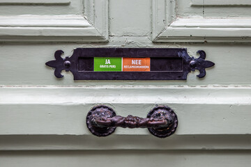 Old door with a letterbox with a sticker with Yes Free Press and No Advertising Prints in Dutch