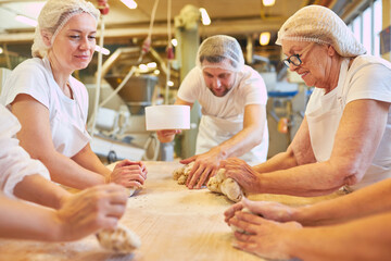 Group of bakers with apprentices kneading the dough