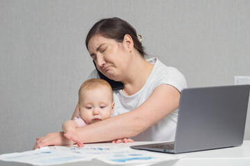 Mother freelancer holding baby on lap talks with colleague on phone analysing important statistics in report. Baby girl looks with concerned expression at woman, selective focus