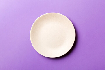Top view of isolated of colored background empty round beige plate for food. Empty dish with space for your design