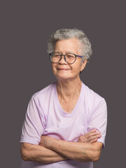 Beautiful elderly Asian woman looking at the camera with a smile while standing on a gray background