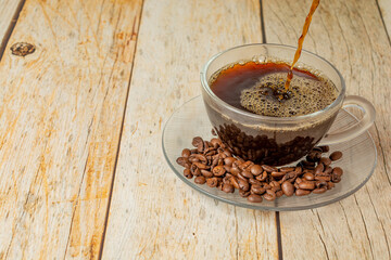 hot coffee and coffee beans on wooden table with filling up cup. text area